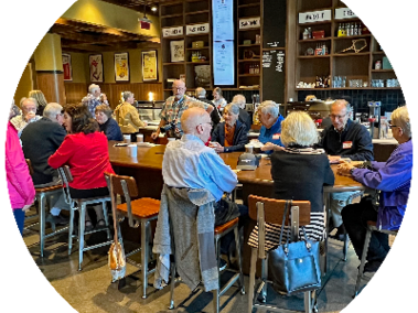 a group of era members are gathered around a table in a coffee shop