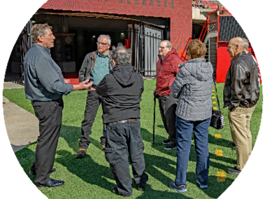 a group of era members stand on memorial field and listen to a tour leader