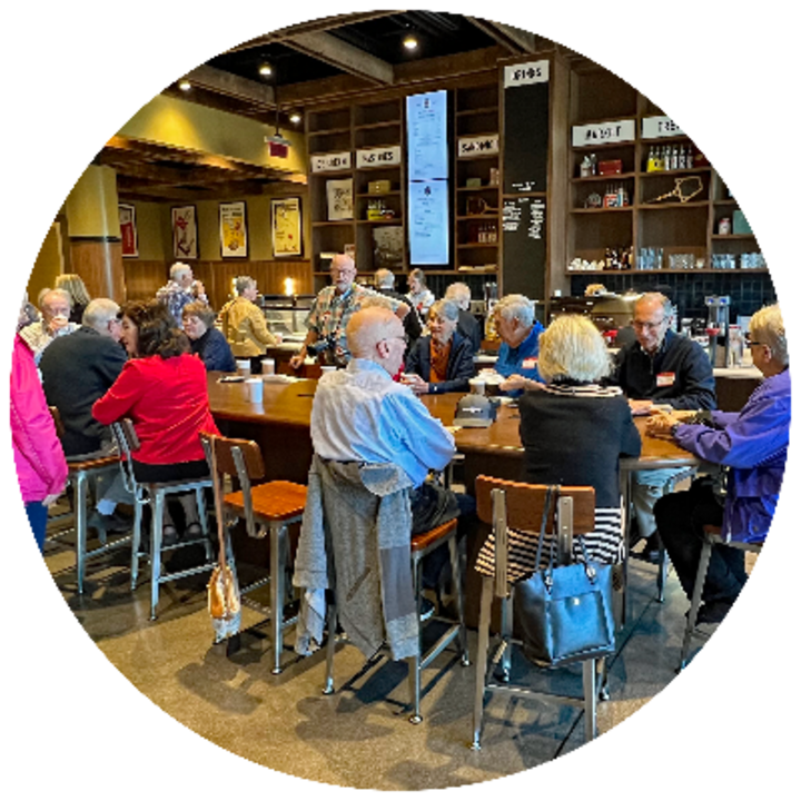 a group of era members are gathered around a table in a coffee shop