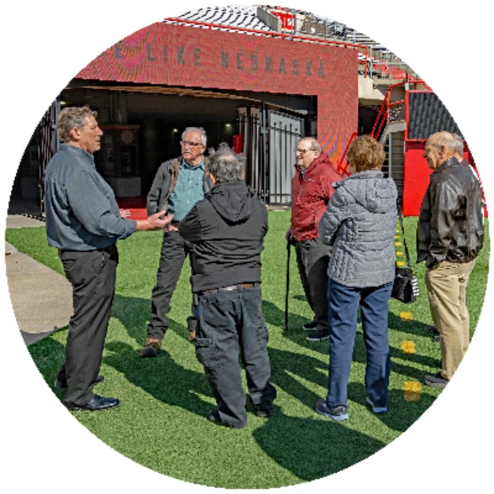 a group of era members stand on memorial field and listen to a tour leader